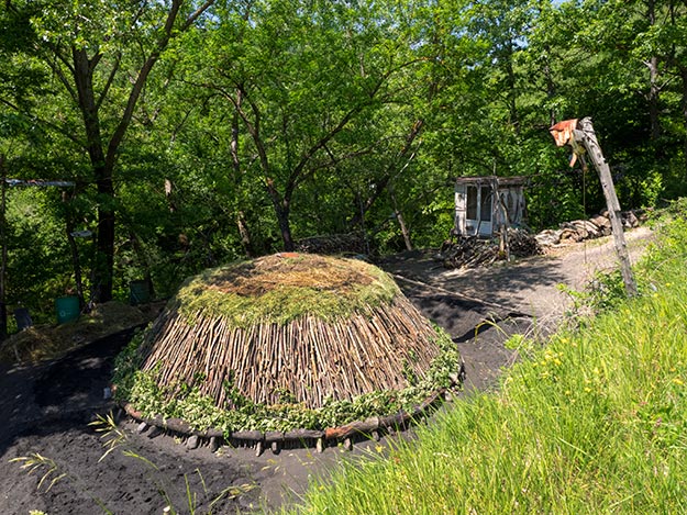 A charcoal kiln is ready to be covered with soil and charcoal ash