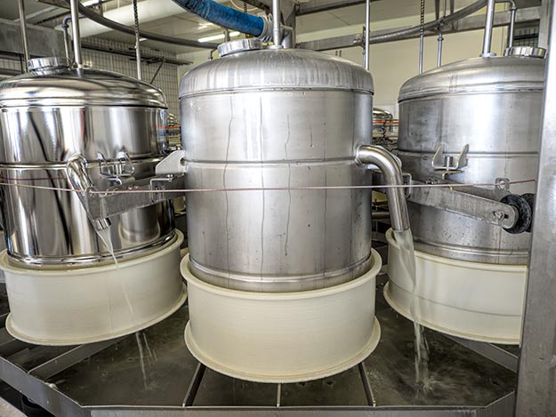 The liquid curd is pumped into tanks where the last of the whey is extracted, after which the remaining curd is pressed into molds