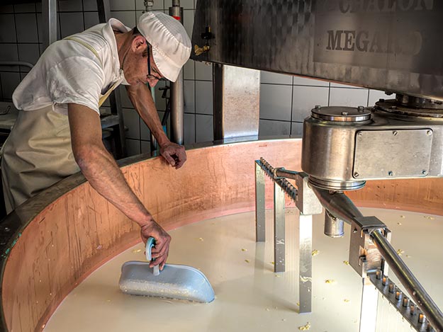 Cheesemaker at Fruitiere of Bouverans performs a clean break test on curd that will become comte cheese