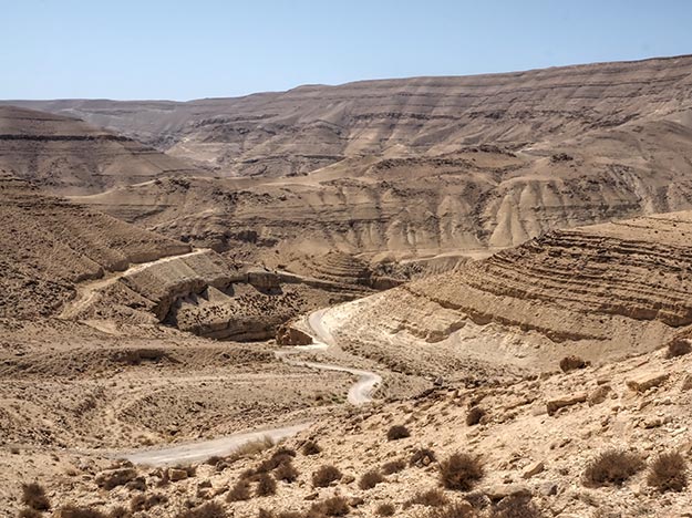 A road to nowhere heads into the depths of Mujib Canyon, Jordan. Read further for my tips on how to book a tour to Petra and Wadi Rum in order to avoid the experience I had.