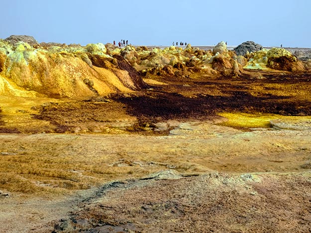 Otherworldy landscape in the Dallol hydro-geothermal sulfur fields. Note the people atop the cliff to get a feeling for the immnsity of the place.