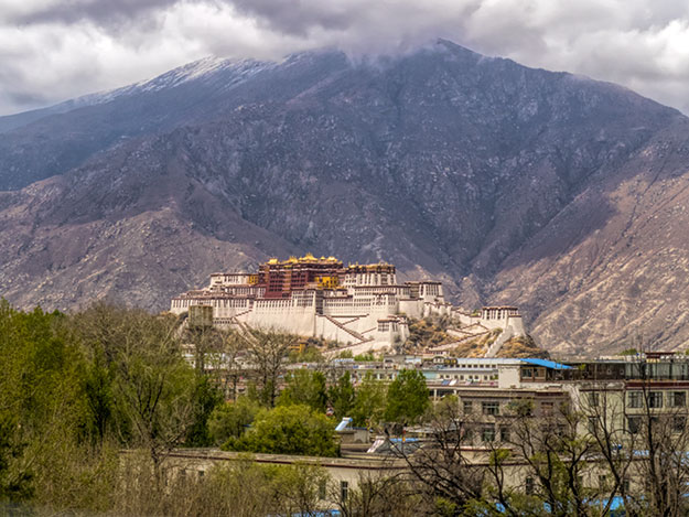 Potala Palace in Lhasa, Tibet, former home to the current Dalai Lama, framed by soaring mountains
