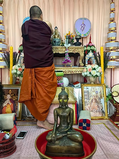 After sealing off Buddha's eyes with yellow beeswax, Phrapalad Thanwa Khayantam retrieves a ball of white string from the altar