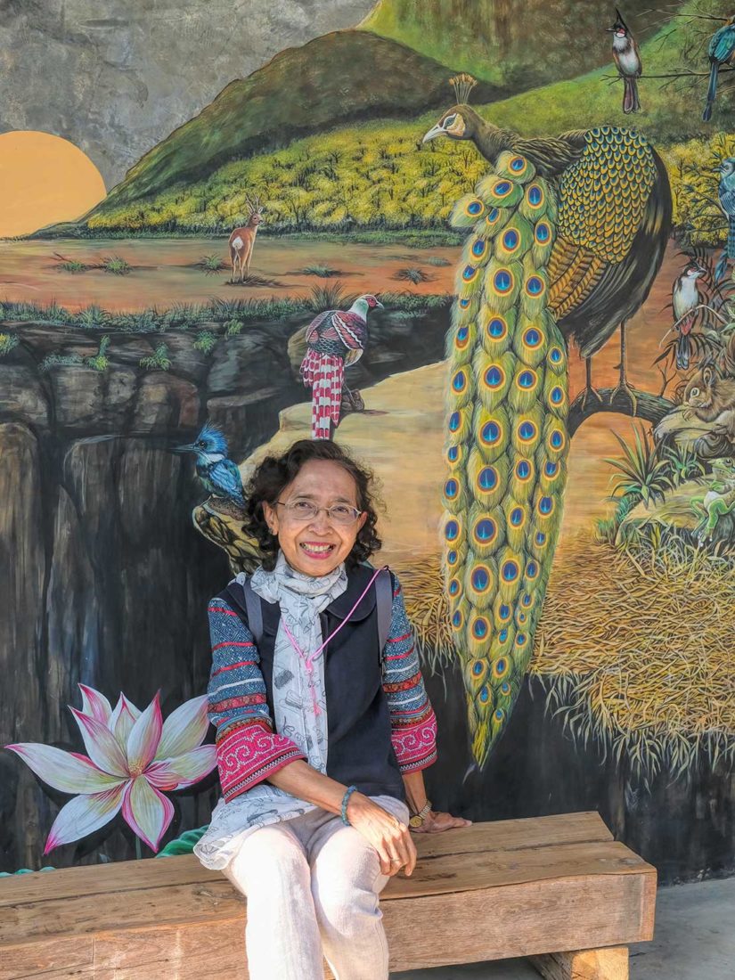 Rosie poses next to an exquisite painting of a peacock