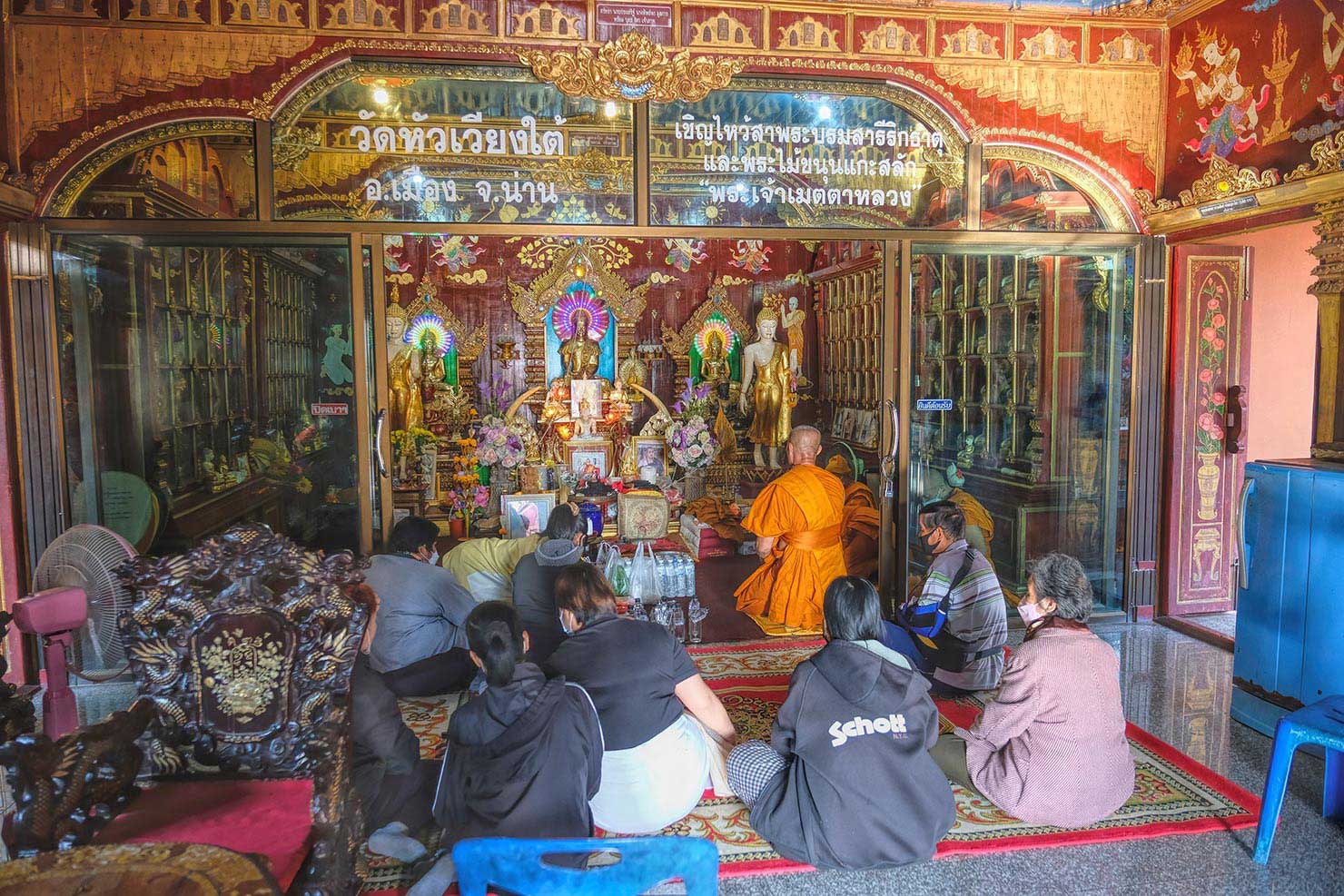 Monks chant the death sutra as the family gathers in the Crematorium during the Buddhist funeral at Wat Hua Weang