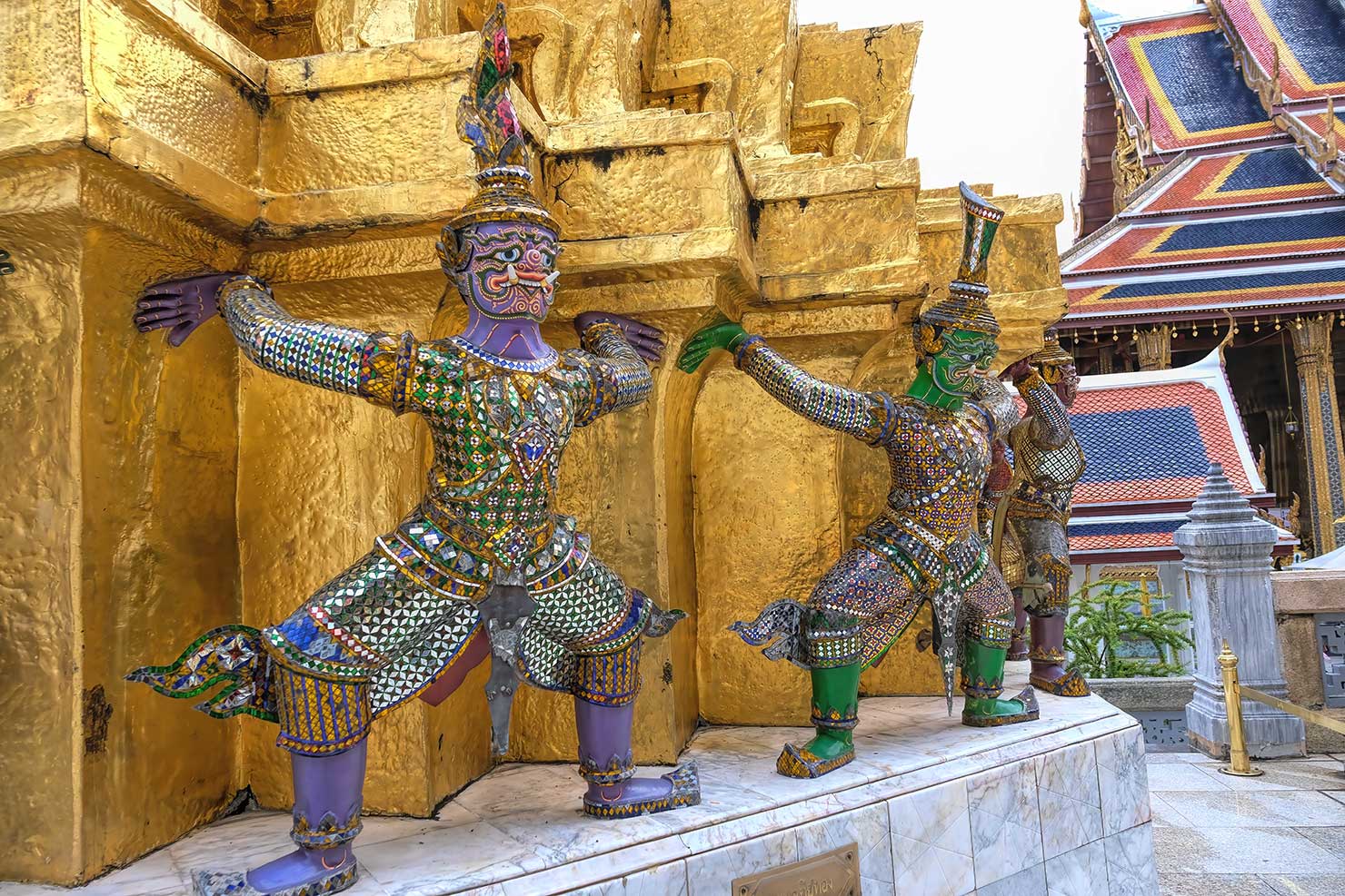 Demons and monkeys support a gilt stupa at the Grand Palace in Bangkok Thailand
