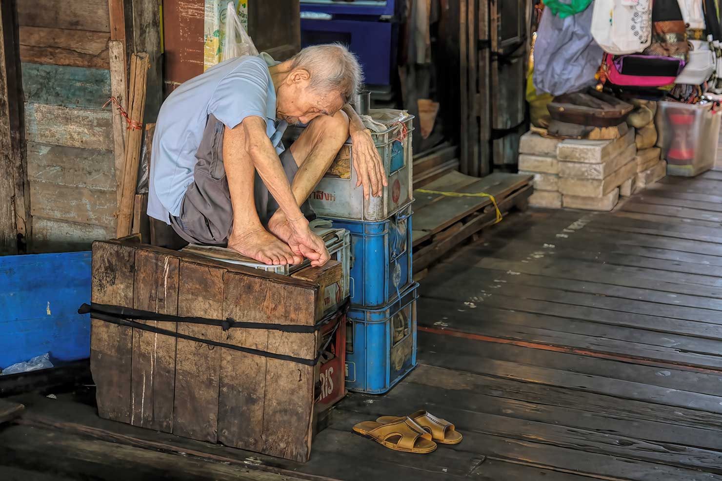 Elderly man takes a nap at Tha Tien Pier in Bangkok