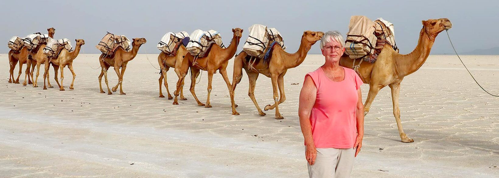 Barbara Weibel in front of a camel caravan carrying salt bocks at the Danakil Depression in Ethiopia, one of the hottest places on earth